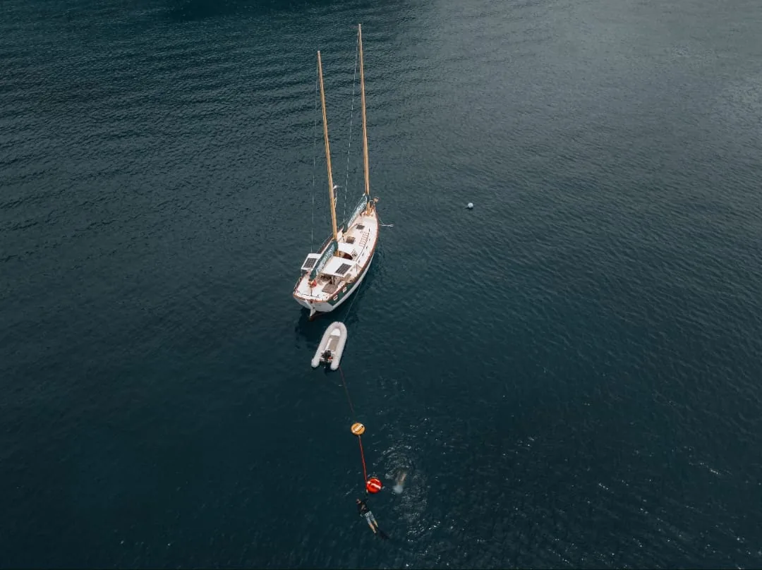 Aerial view of SV Freedom Fargo at anchor with her dinghy and buoy line